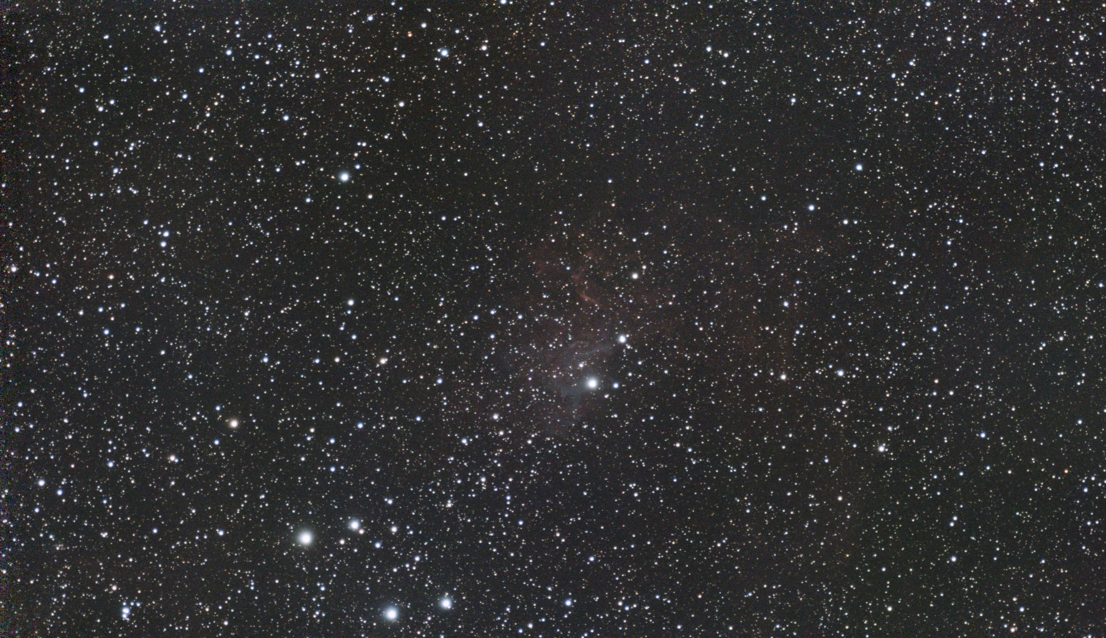The faint red Flaming Star Nebula around a bright star in a dense star field